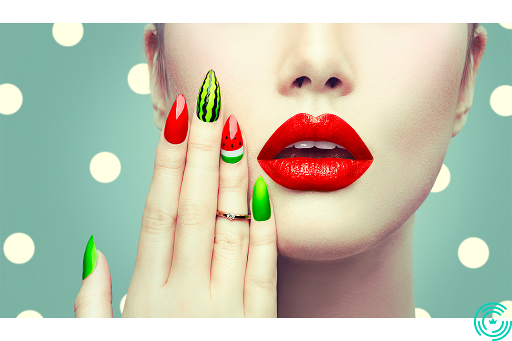 The face of a woman and her hand with a manicure in shades of red and green