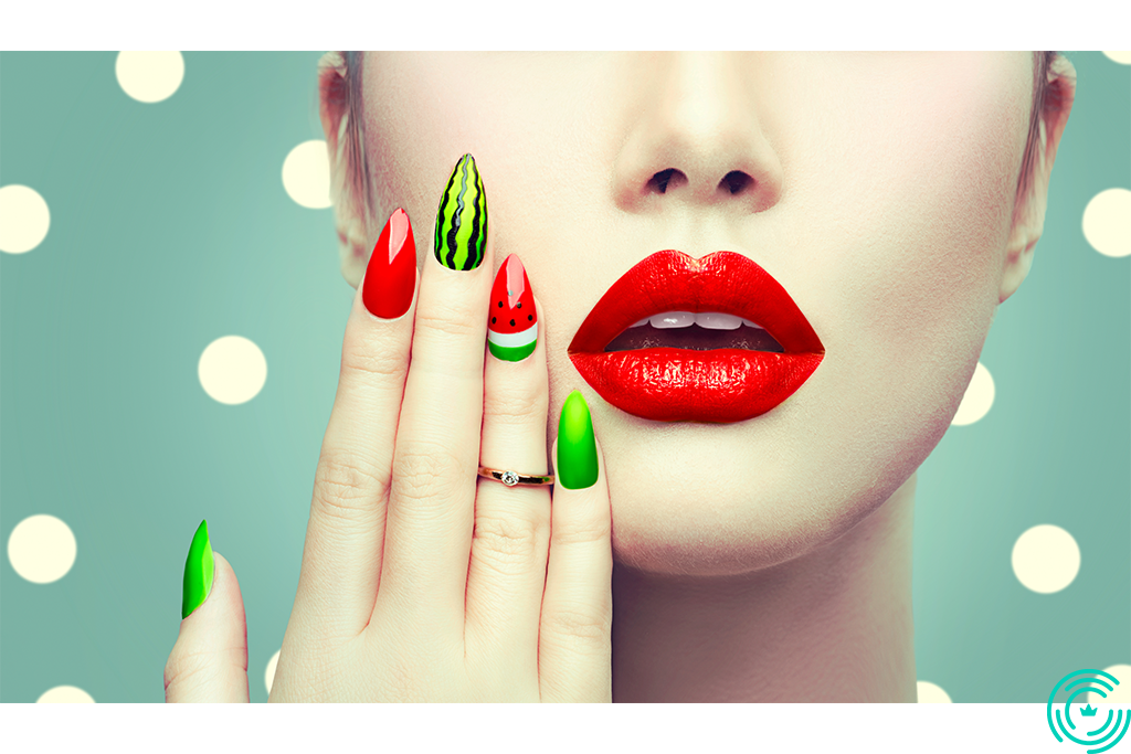 The face of a woman and her hand with a manicure in shades of red and green