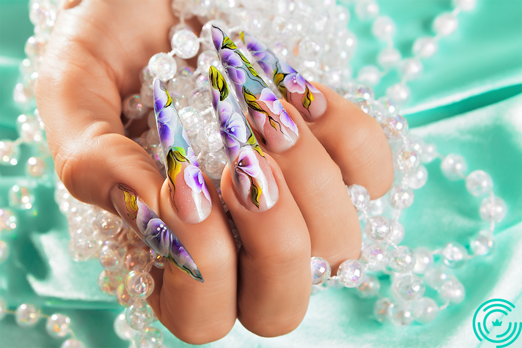 Woman's hand with very long and sharp nails and floral pattern applied on them